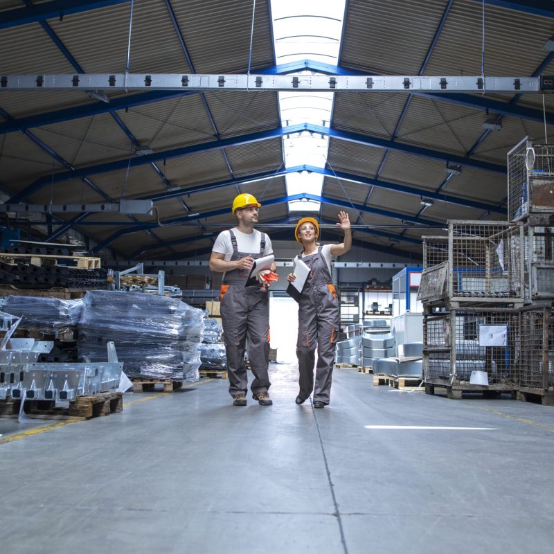 Factory workers walking through large production hall.